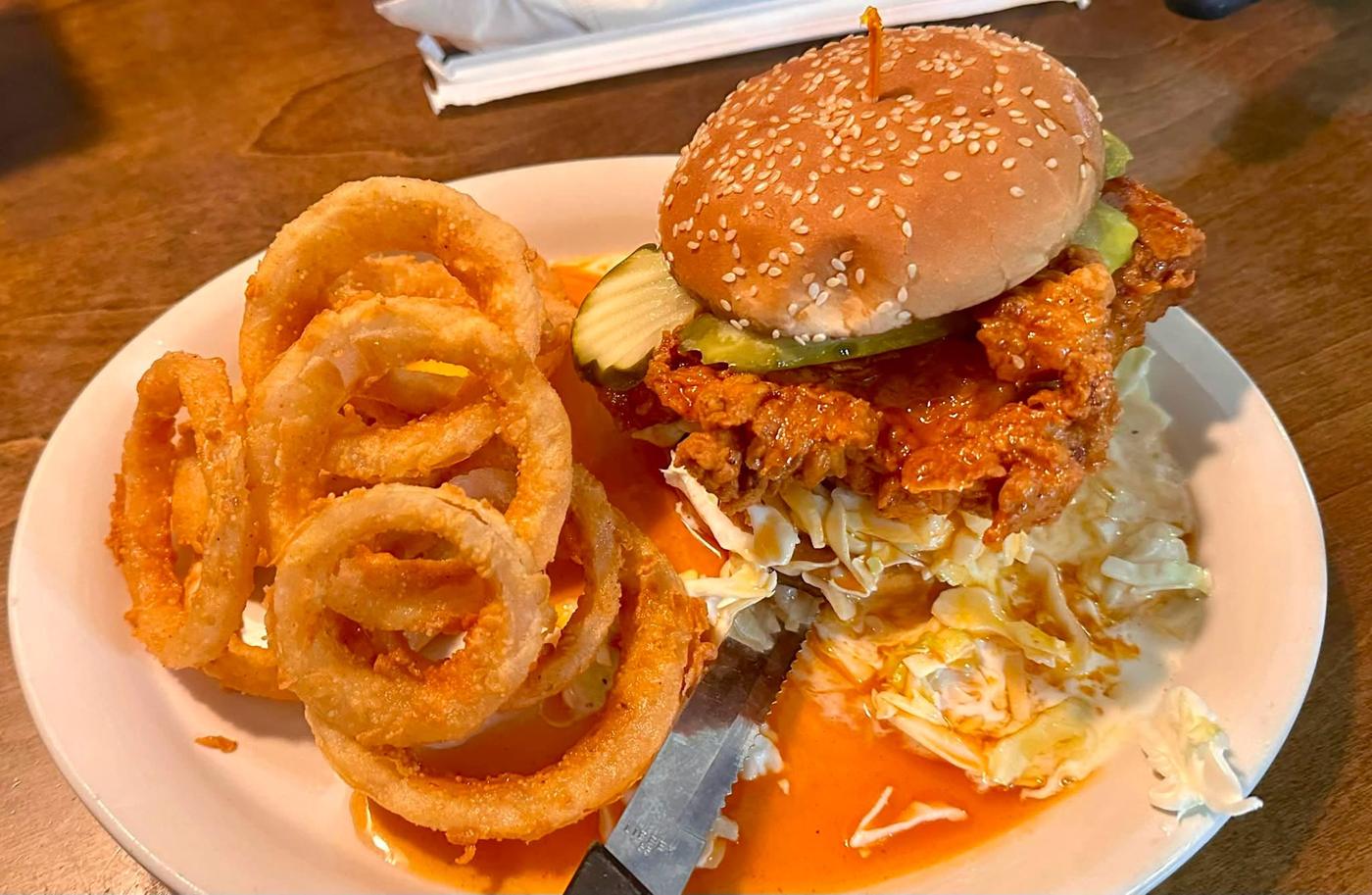 Fried chicken sandwich with slaw served alongside onion rings