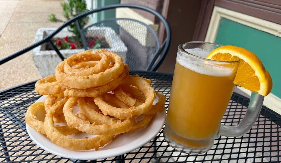 A plate of onion rings and a cold beer on a patio table outside the Anvil Saloon